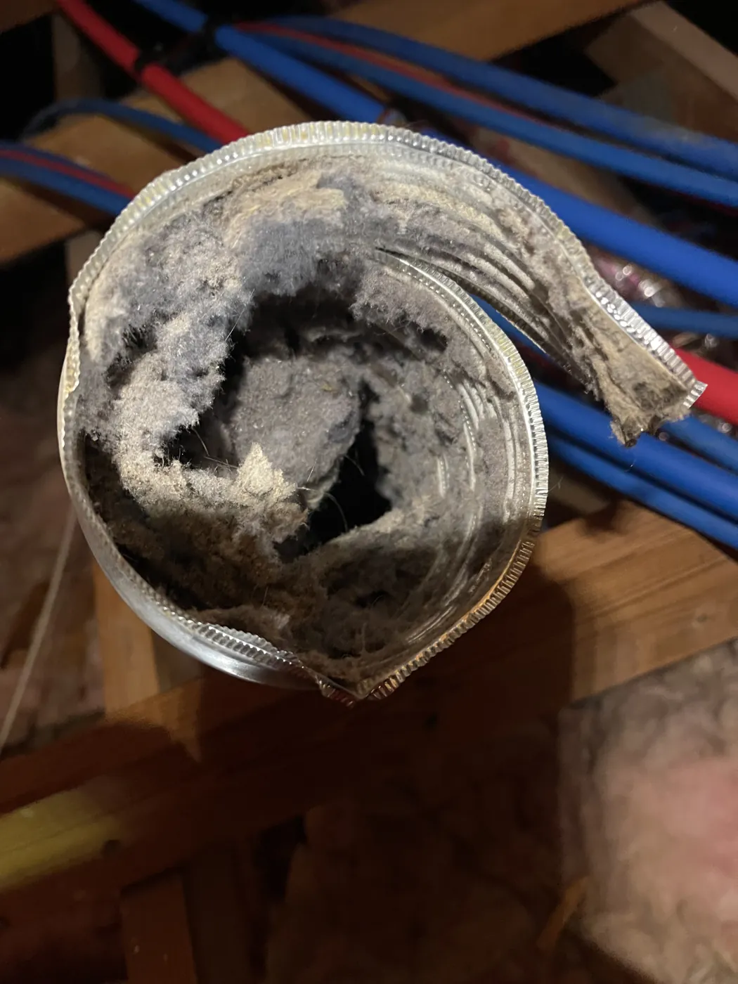 A flex duct collar rolled back, its interior caked with dust